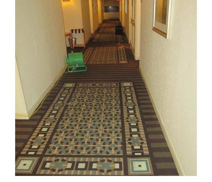 long hotel hallway, with colorful carpeting being dried out by SERVPRO equipment