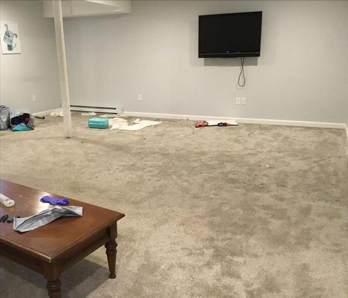 Partially finished basement with noticeable wet carpet and scattered contents on the floor